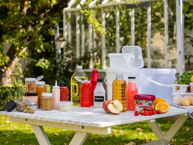 Picnicbord med plastikflasker og plastikglas til mad